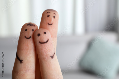 Murais de parede Three fingers with drawings of happy faces on blurred background, space for text