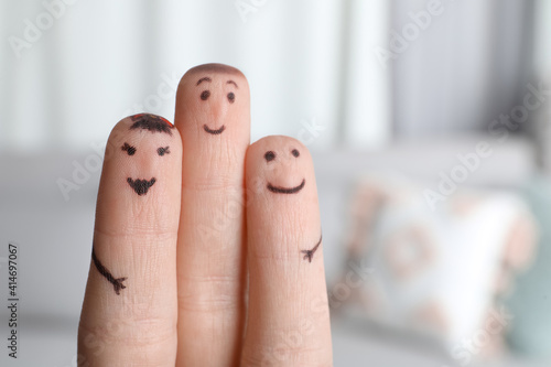 Three fingers with drawings of happy faces on blurred background
