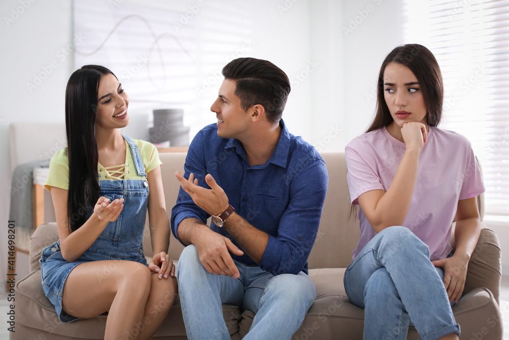 Unhappy woman feeling jealous while couple spending time together at home Unhappy woman feeling jealous while couple spending time together at home