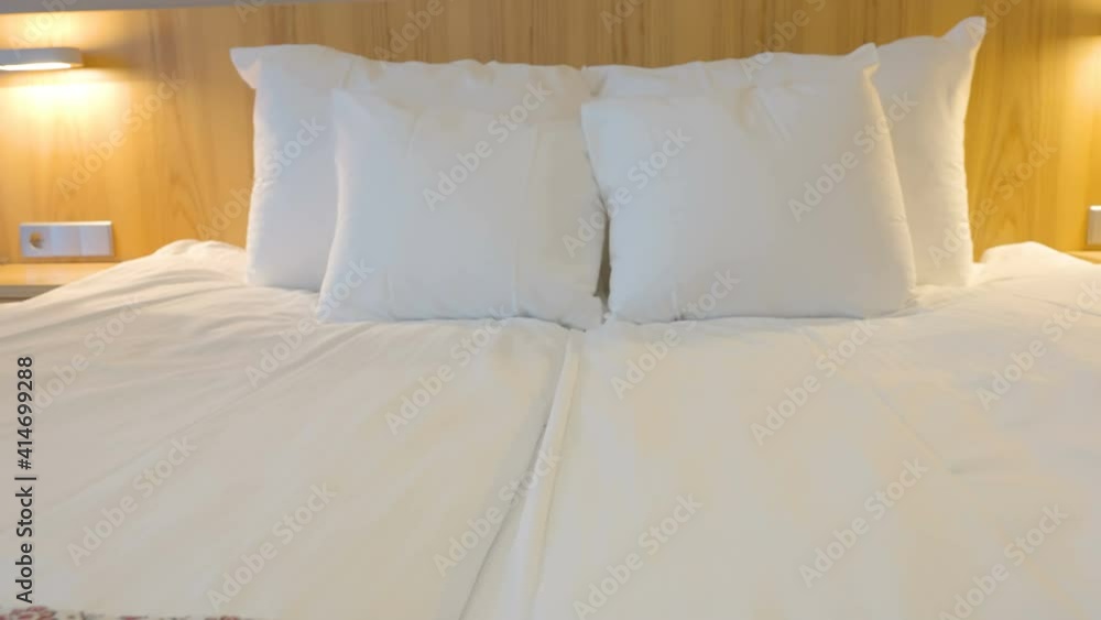 A look of the clean bed with the white sheet and pillows on the headboard A look of the clean bed with the white sheet and pillows on the headboard