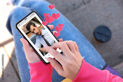 Woman visiting dating site via smartphone outdoors, closeup