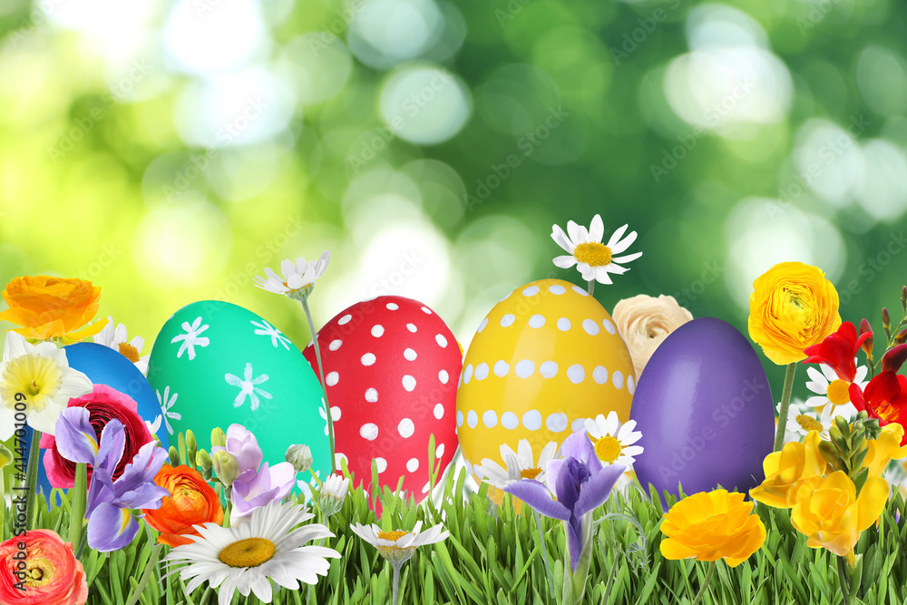 Bright Easter eggs and spring flowers on green grass outdoors Bright Easter eggs and spring flowers on green grass outdoors