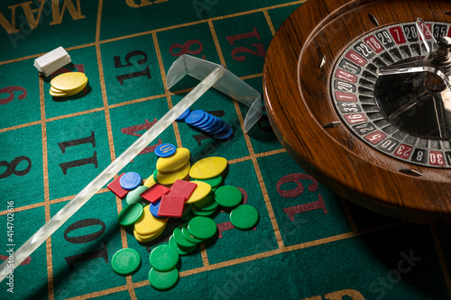 Roulette in legno isolata sopra un tavolo da gioco verde con fiches colorate photo
