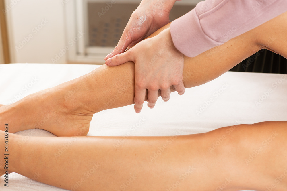 Relaxed young woman having healing body massage. Close-up of the hands of female massage therapist massaging legs of young caucasian lady in spa salon. Body care, massage, spa concept. Relaxed young woman having healing body massage. Close-up of the hands of female massage therapist massaging legs of young caucasian lady in spa salon. Body care, massage, spa concept.