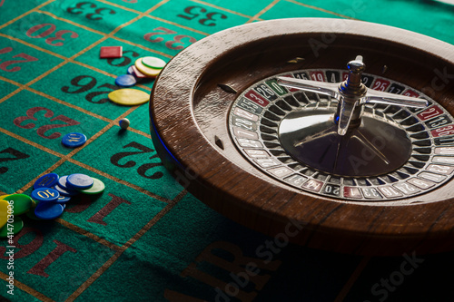 Roulette in legno isolata sopra un tavolo da gioco verde con fiches colorate