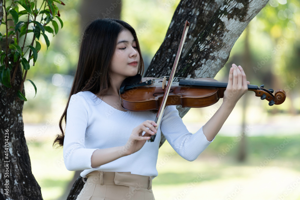 Beautiful woman hold violin on nature view background, in emotion feeling happy.