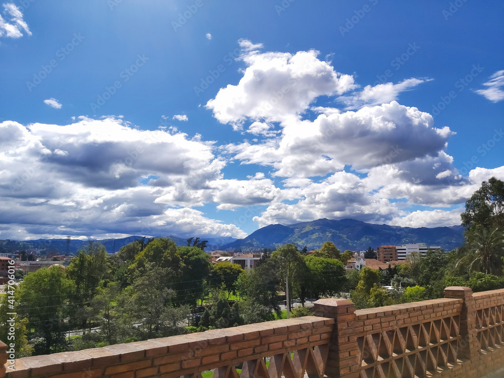 Mountainous landscape, part of the city of Cuenca, seen from a reddish brick balcony.