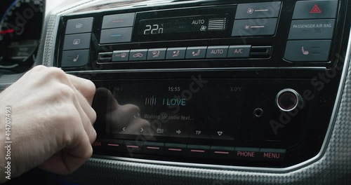 Driver changing car radio volume while driving photo