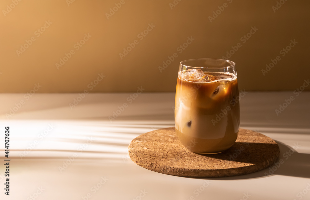 Fototapeta Glass of a iced coffee with cream milk. Cold brew coffee drink with ice. Early morning sun light. Copy space.