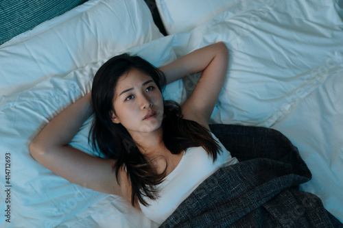 young beautiful asian korean woman at home bedroom lying in bed late at night trying to sleep suffer insomnia sleeping disorder. girl scared on nightmares look sad worried in mental health concept
