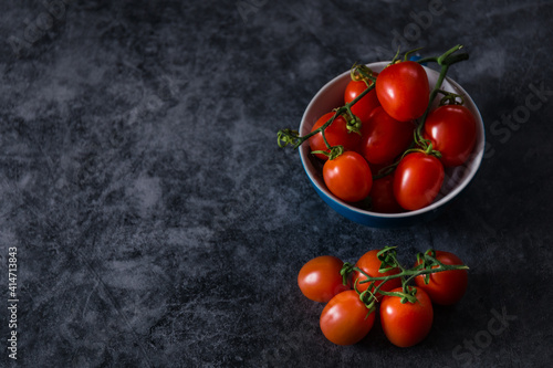 fresh tasty cherry tomatoes on dark stone background with copy space