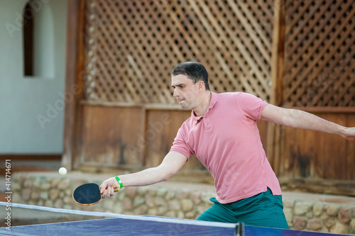 The man playing table tennis in pink shirt
