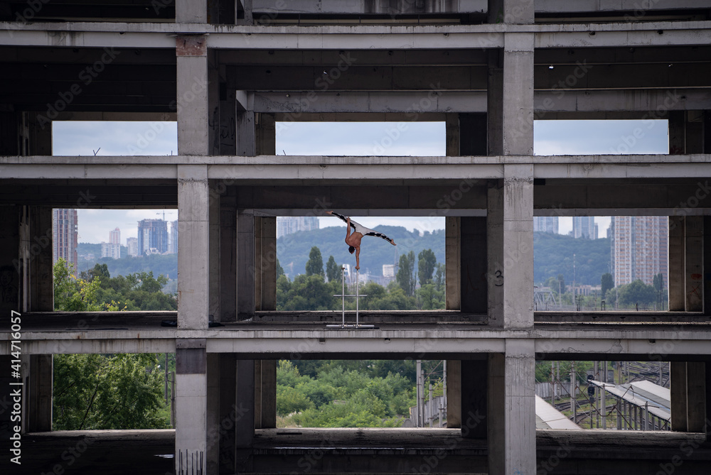 Fototapeta premium Flexible male circus Artist keep balance by one hand in the concrete structure. Individuality, outstanding and originality.