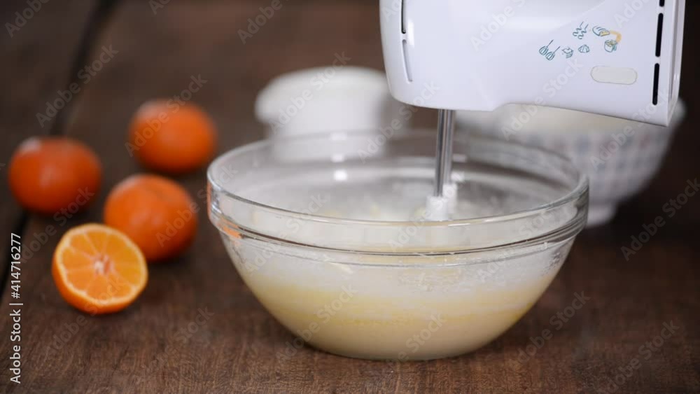 Woman in kitchen cooking a cake. Hands beat the dough with an electric mixer. Woman in kitchen cooking a cake. Hands beat the dough with an electric mixer.
