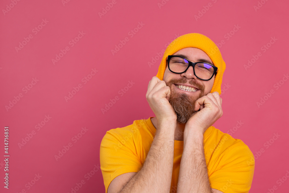 Portrait of stylish handsome european bearded man in casual yellow shirt hat and glasses on pink background Portrait of stylish handsome european bearded man in casual yellow shirt hat and glasses on pink background