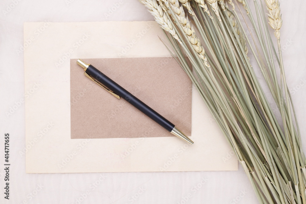 Czarno złoty długopis na beżowej kartce i suszone kwiaty  - obrazy, fototapety, plakaty 