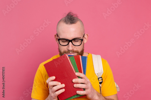 Adult student cheerful casual wear guy with beard and backpack holding books isolated on pink background