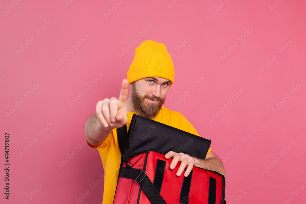 European bearded delivery man open box with food and pointing finger to camera wait sign on pink background isolated