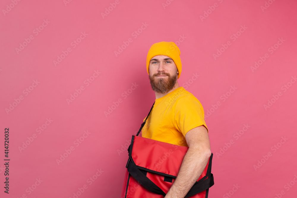 European bearded delivery man with box with food  pink background isolated