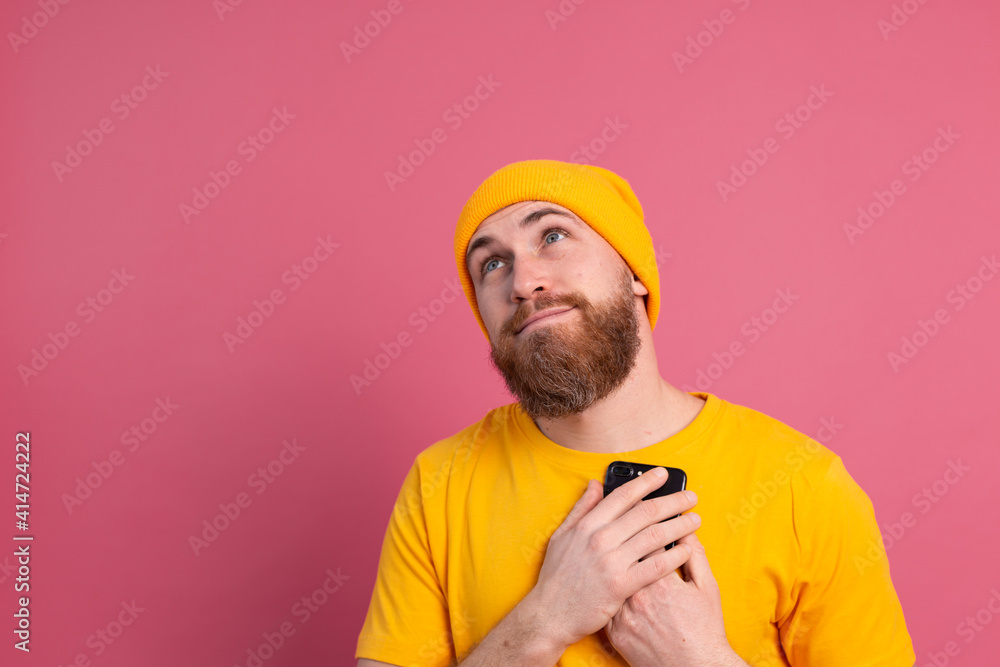 European man got lovely message, holding mobile phone smiling on pink background European man got lovely message, holding mobile phone smiling on pink background