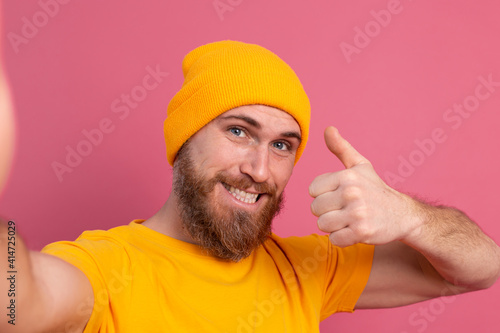 Strong handsome muscular happy cheerful man casual style take photo selfie on pink background