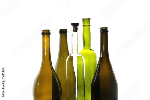 Still life with transparent wine bottle with wine stopper and green wine bottle among brown empty wine bottles isolated on white background