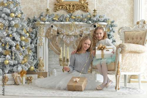 Cute little girls with presents near decorated Christmas tree