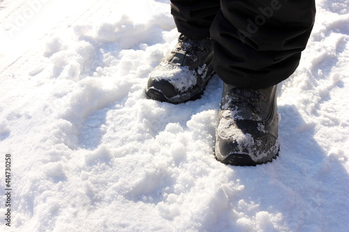 men's feet in winter boots are walking in the snow.