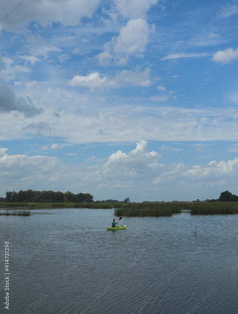 hombre remando en kayak laguna cielo despejado
