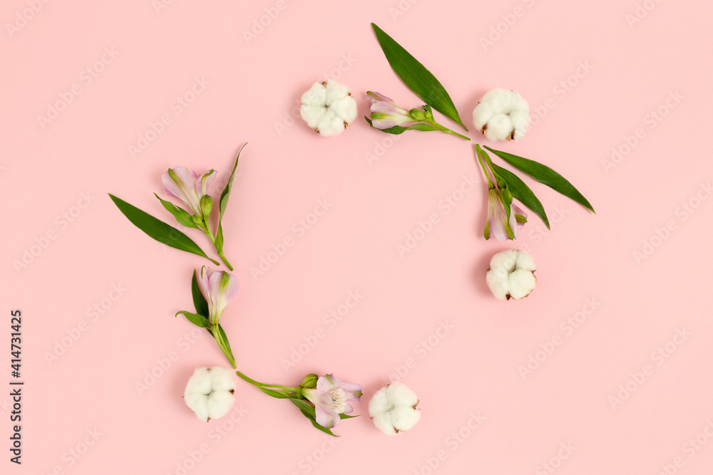 Fototapeta premium Square frame made of alstroemeria flowers, cotton and green leaves on a pink pastel background. Holiday floral composition.
