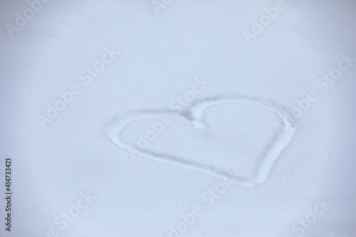 Snow heart drawing as winter background top view concept.