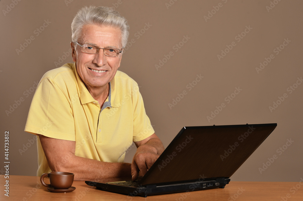 Smiling senior man sitting at table with laptop Smiling senior man sitting at table with laptop