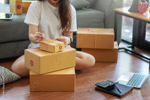 Young woman entrepreneur working packing the order for shipping to customer at house.