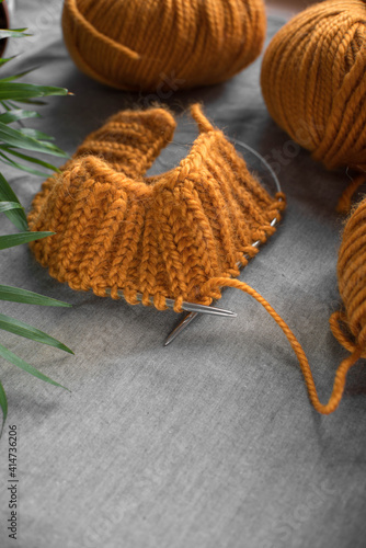 Fototapeta Naklejka Na Ścianę i Meble -  bright balls of orange woolen thick yarn and knitting on a gray wrinkled background with place for text