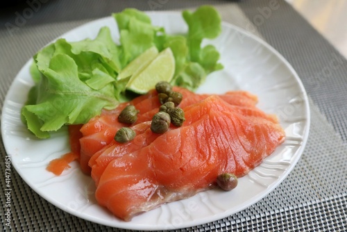 Smoked salmon with lemon and vegetable on white plate. Food concept.