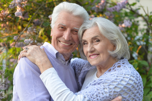 portrait of beautiful senior couple by lilacs in the park
