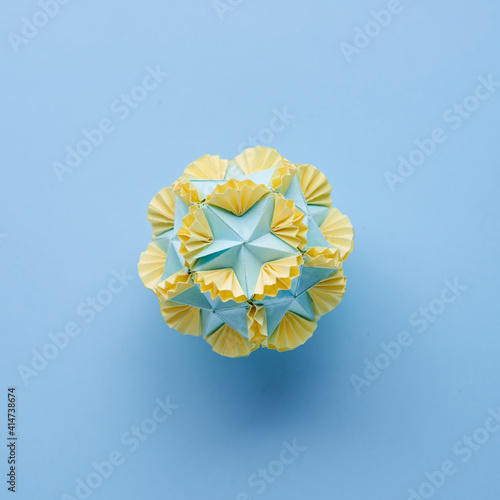 Multicolor handmade modular origami ball or Kusudama Isolated on blue background. Visual art  geometry  art of paper folding  paper crafts. Top view  close up  selective focus  copy space.