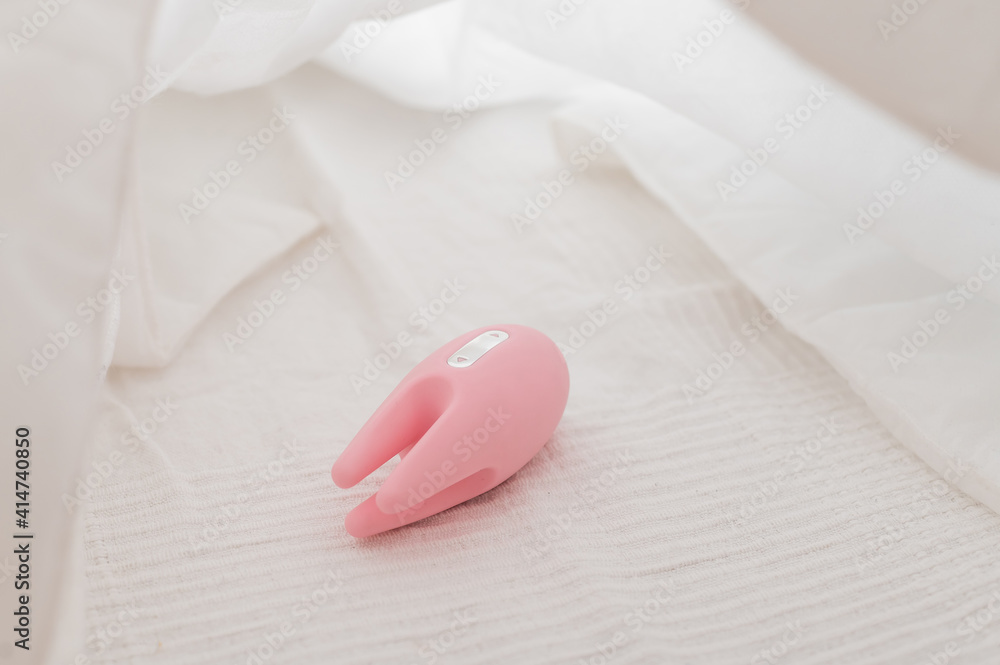 Close-up of a clitoral vibrator on a white sheet on the bed Close-up of a clitoral vibrator on a white sheet on the bed