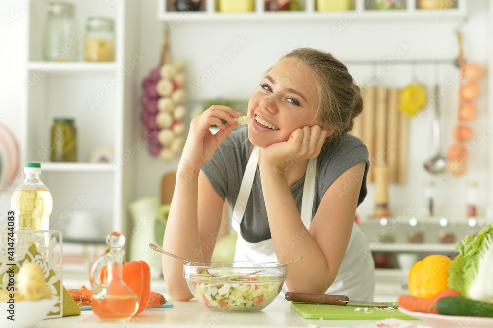 Beautiful young woman eating salad at home