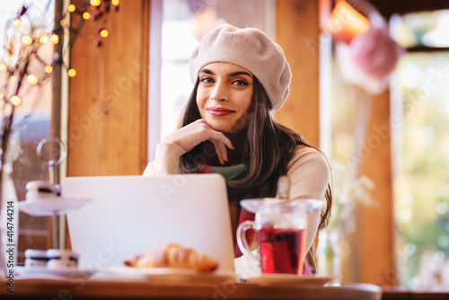 Attractive young woman using her laptop while sitting at cafe desk