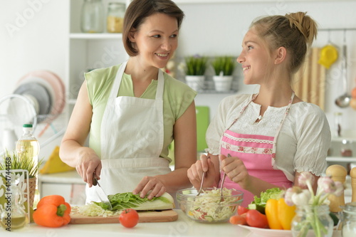 teenager  girl with her mother cooking together at kitchen table