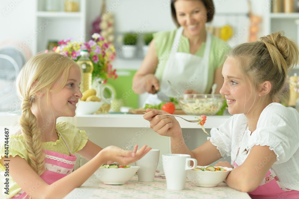 Cute girls eating delicious fresh salad in kitchen Cute girls eating delicious fresh salad in kitchen
