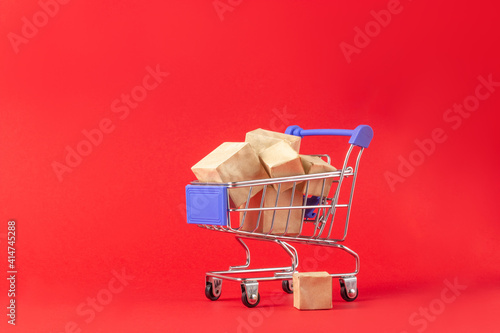 Shopping basket and boxes with purchases with place to add text on a red background. Online shopping and sale concept