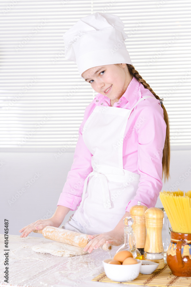 Cute girl in chef's hat baking cake in the kitchen Cute girl in chef's hat baking cake in the kitchen