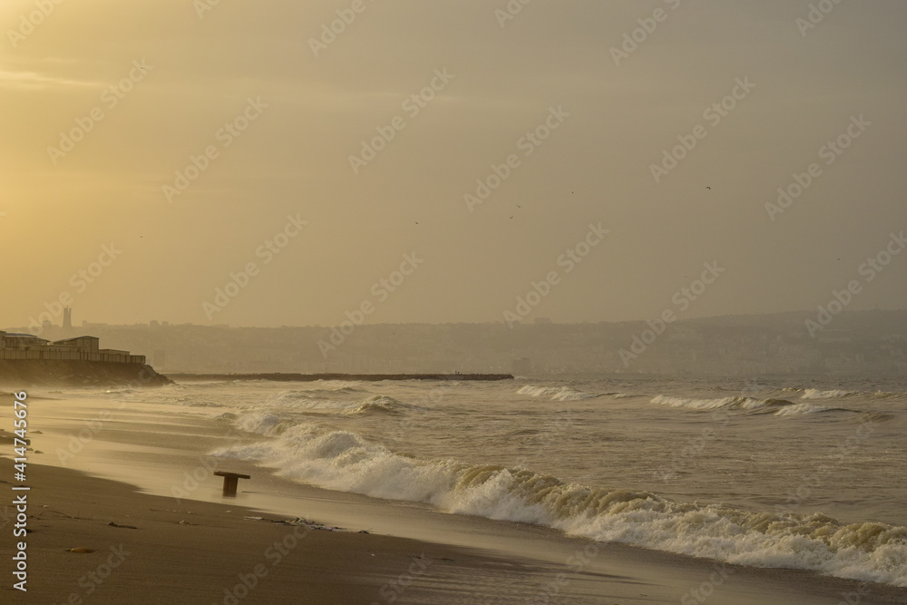 A beautiful view of sea waves on the sand beach and Algiers city in the background A beautiful view of sea waves on the sand beach and Algiers city in the background