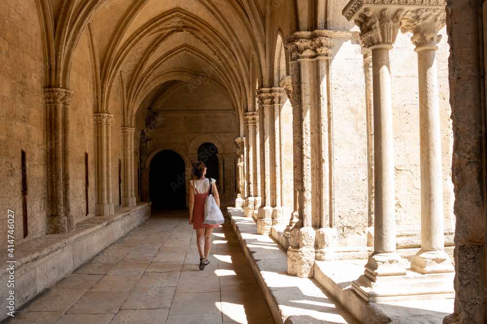 Tourist woman visiting the cloister of the cathedral of Arles, France, - obrazy, fototapety, plakaty 