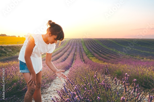 Fototapeta Naklejka Na Ścianę i Meble -  Cute girl touching flowers in a french lavender field at sunset