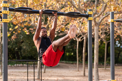 african american athlete boy does calisthenics fitness exercises on bars in park