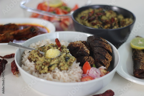 Kerala meals with red rice, sardines curry, sardine fry and coconut based green gram curry photo