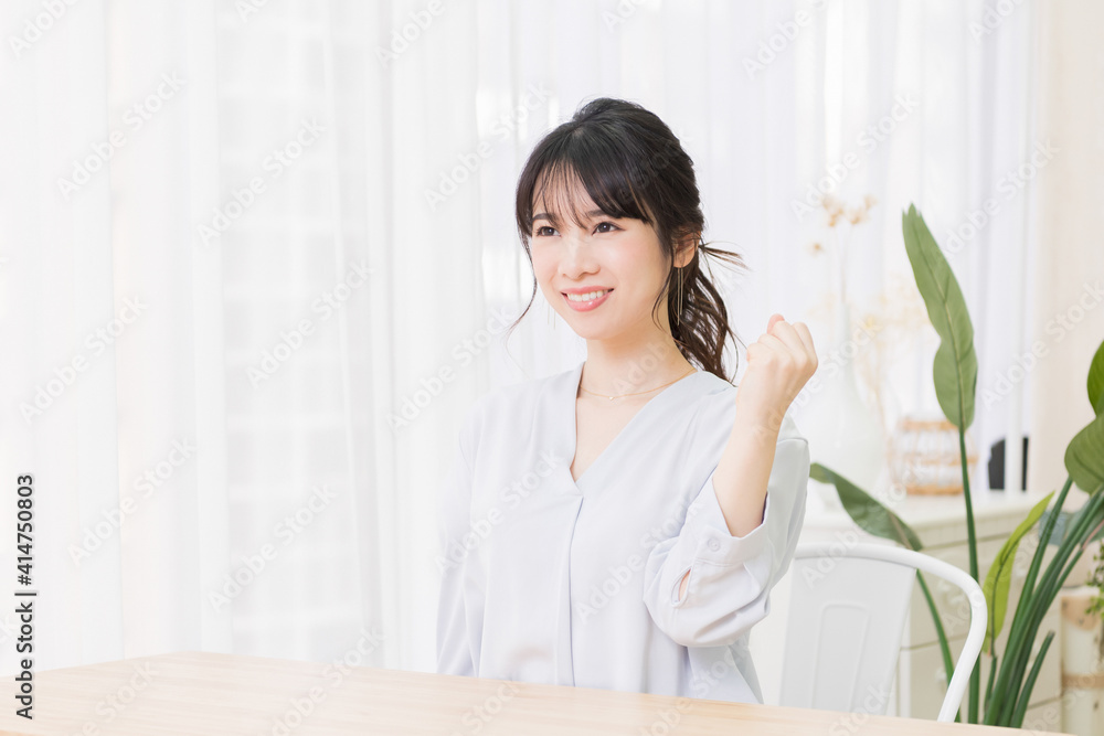 部屋でガッツポーズをする若い女性 部屋でガッツポーズをする若い女性